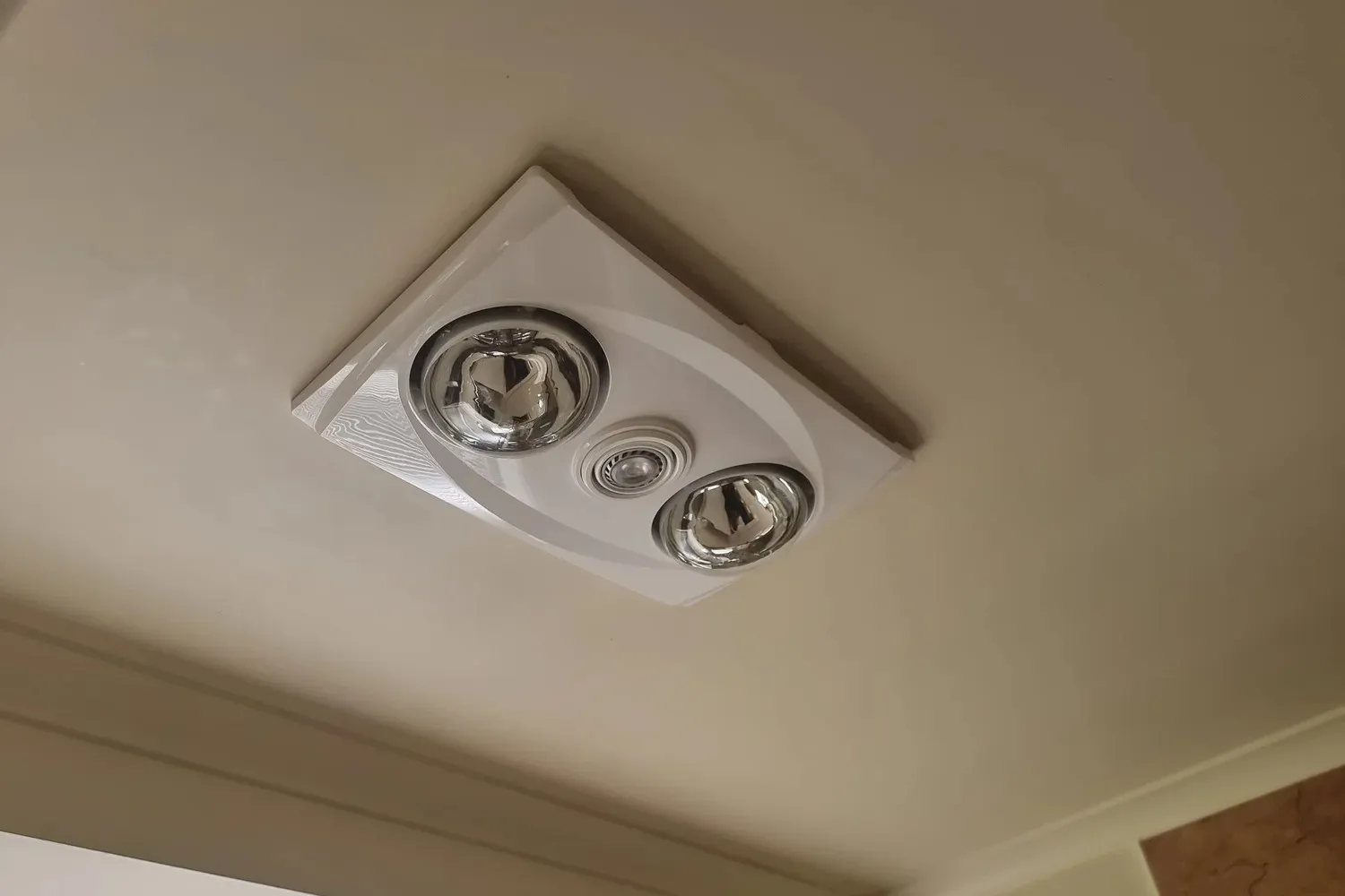 A white heat, light and fan unit fitted in a bathroom ceiling.